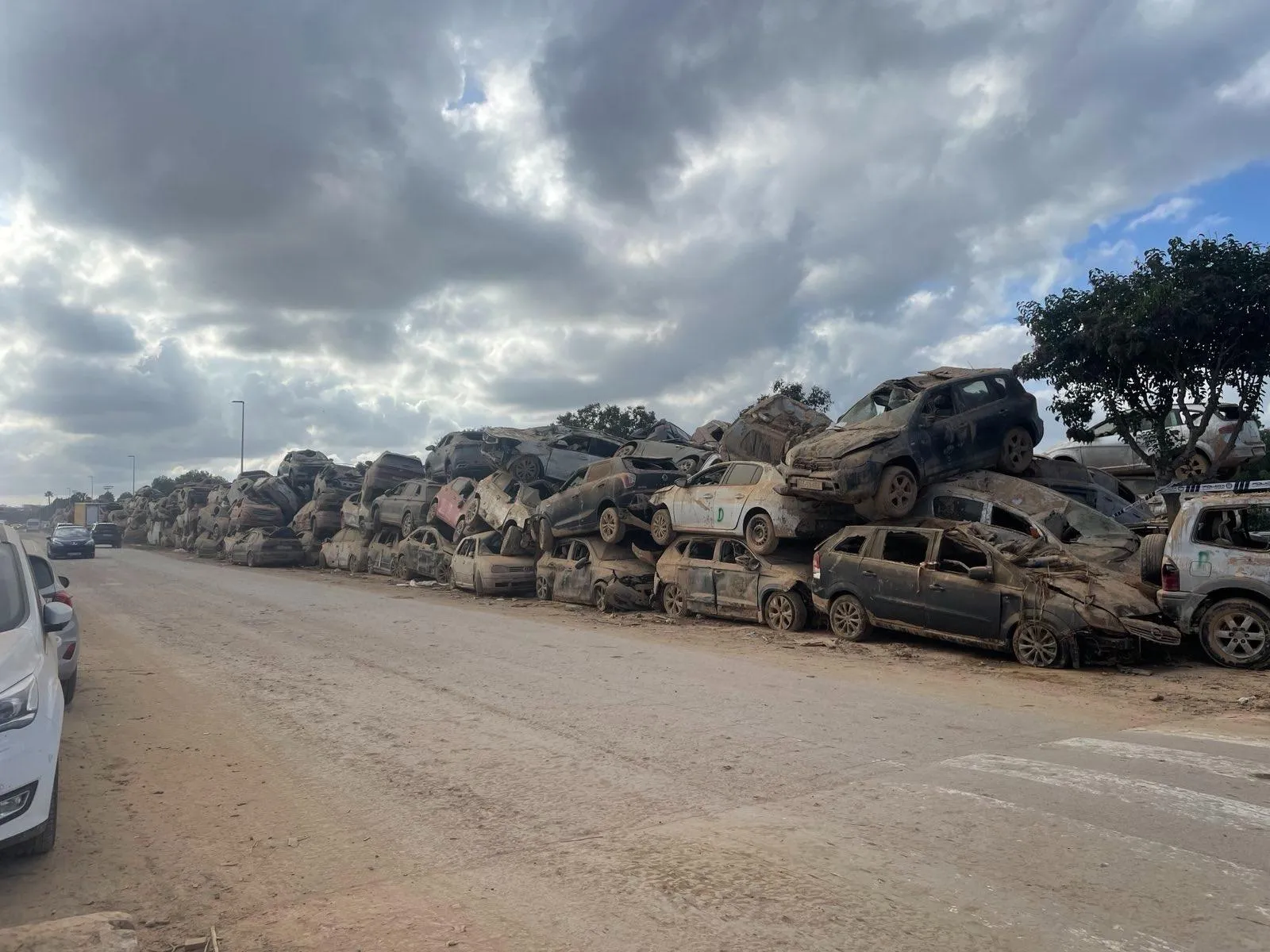 Flood-damaged cars piled up next to the road.